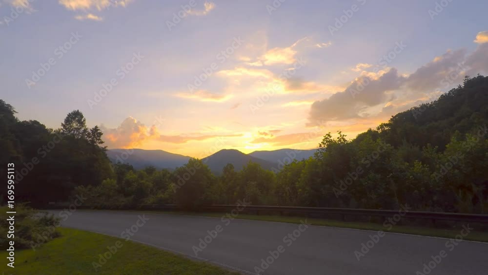 Great Smoky Mountains National Park with sunset clouds moving over mountain peaks behind paved road in Santeetlah Gap, Cheoah, North Carolina, USA Great Smoky Mountains National Park with sunset clouds moving over mountain peaks behind paved road in Santeetlah Gap, Cheoah, North Carolina, USA