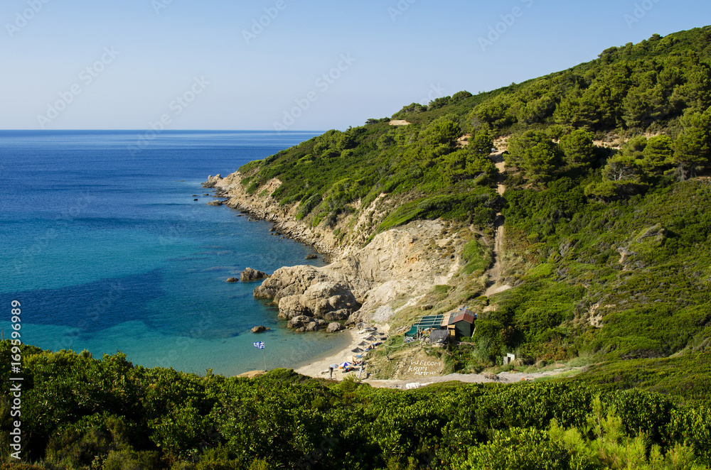 View from the top of the beach of Krifi Ammos on the island of Skiathos Greece, the sea is green and turquoise surrounded by rich vegetation