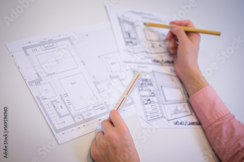 Mão de mulher trabalhando,  desenhando em mesa branca uma planta baixa arquitetônica, engenheira, construção. photo