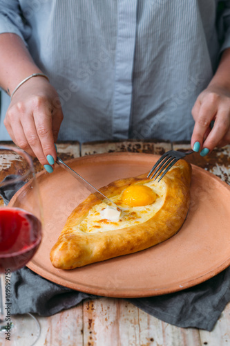 woman having traditional georgian lunch or dinner of khachapuri and wine served on wooden table