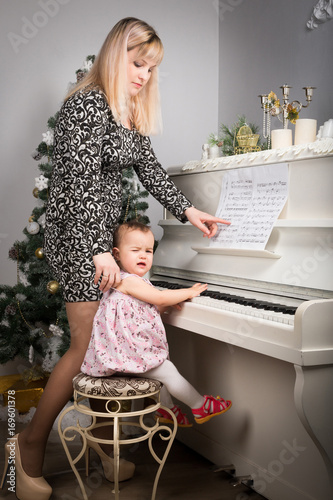 Baby is learning to play the piano at his mother's lap. Babe crying photo