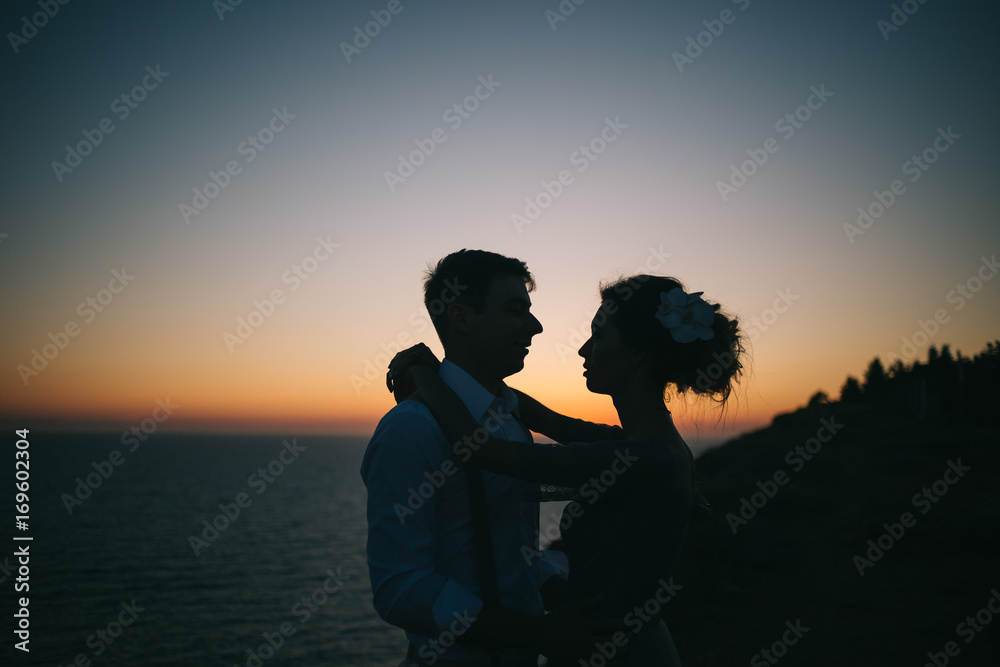 Beautiful sunset at sea, a man and a woman hugging and looking at each other, close-up