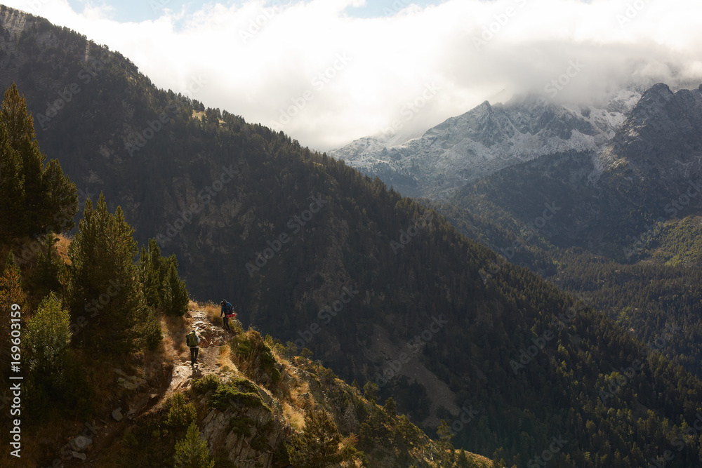 Hikers on a mountain ridge trail with a beautiful scenery Hikers on a mountain ridge trail with a beautiful scenery