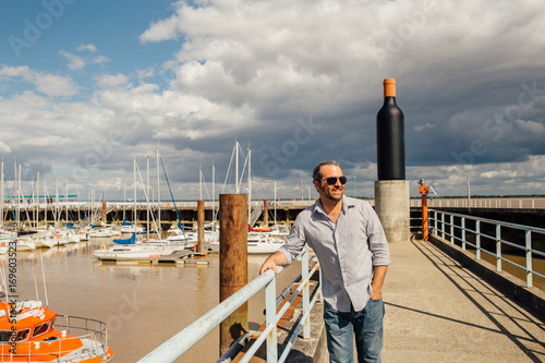 A Man Wearing Sunglasses Walks on a Pier