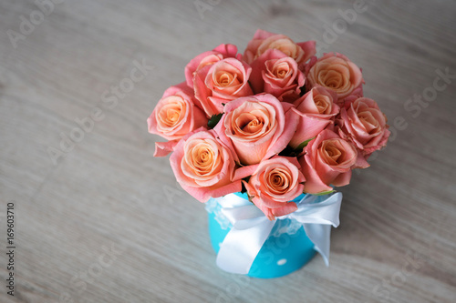 pink-orange roses in a turquoise box tied with a bow