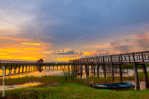 Beautiful golden sunset  row boat and a wooden bridge at pond. Fantastic vivid twilight at Sam Roi Yod National Park  Prachuap Khirikhan  Thailand.