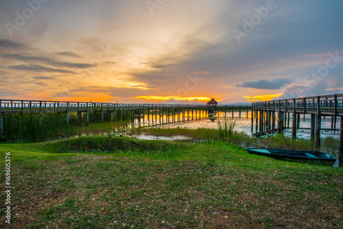 Beautiful golden sunset  row boat and a wooden bridge at pond. Fantastic vivid twilight at Sam Roi Yod National Park  Prachuap Khirikhan  Thailand.