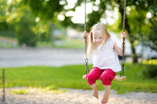 Cute little girl having fun on a playground outdoors in summer. © MNStudio