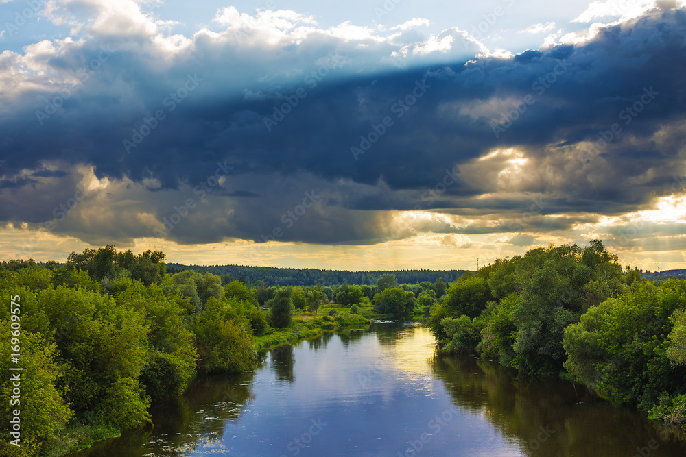 Evening landscape with dramatic sky with clouds and river