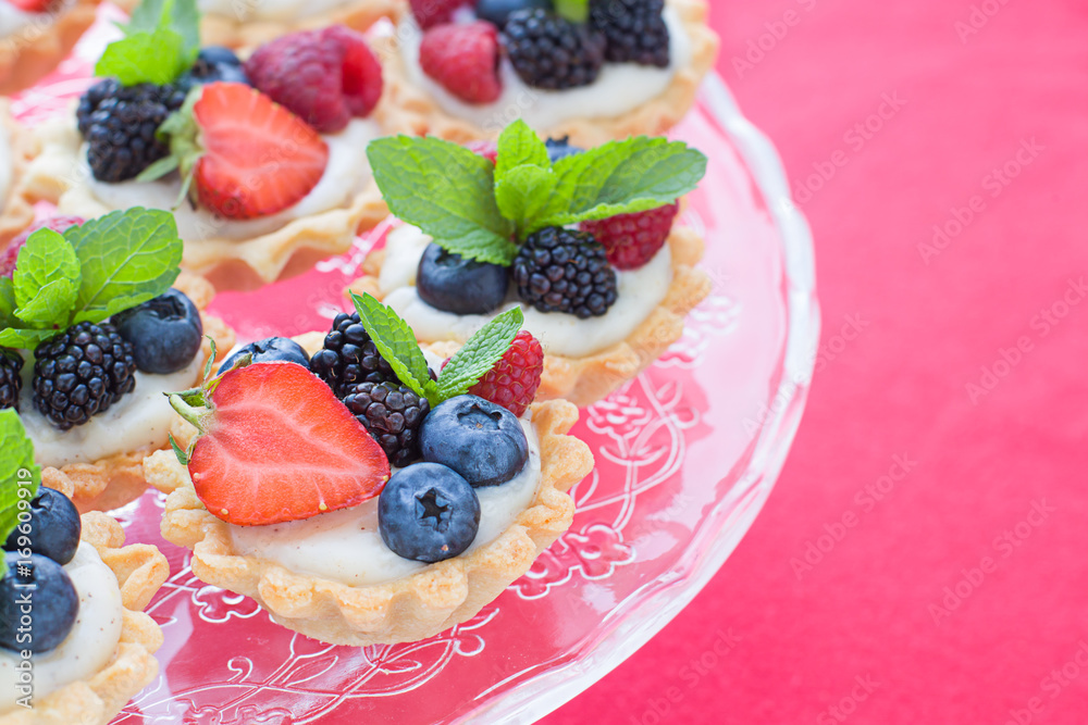 Mini tarts on the plate close up. Homemade dessert with delicious catalonian traditional cream and fresh berries Mini tarts on the plate close up. Homemade dessert with delicious catalonian traditional cream and fresh berries