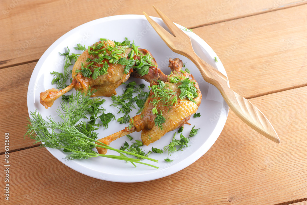 Fried duck leg on a white plate sprinkled with herbs for a restaurant Fried duck leg on a white plate sprinkled with herbs for a restaurant