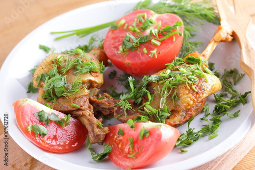 Roasted duck legs with tomato and herbs with wooden cutlery