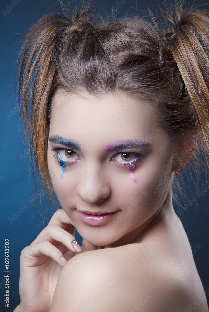 Fototapeta premium Close-up portrait of girl with bright makeup and clean skin on blue background