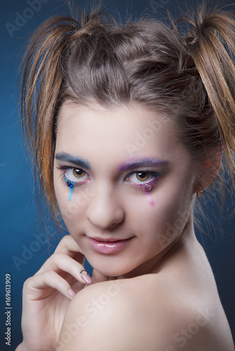 Close-up portrait of girl with bright makeup and clean skin on blue background