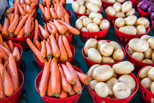 New fresh crop of carrots and gold potatoes on display at farmers market in baskets