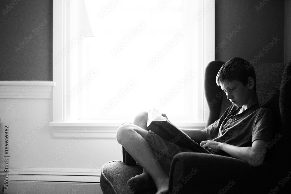 teen reading in a corner by the window