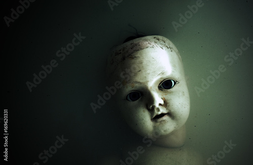 Fotografiet Creepy doll face in dark dirty water
