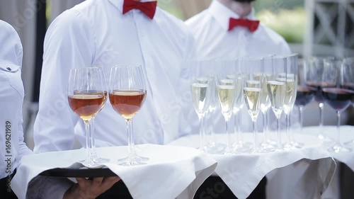 The waiters greet guests with alcoholic drinks. Champagne, red wine, white wine on trays. photo