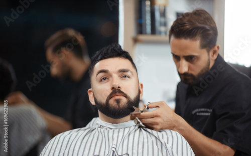 Hairstylist working at barbershop cutting bread with scissors.