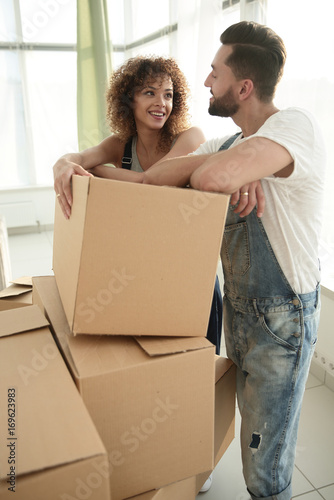 Happy couple standing near boxes in their new apartment.