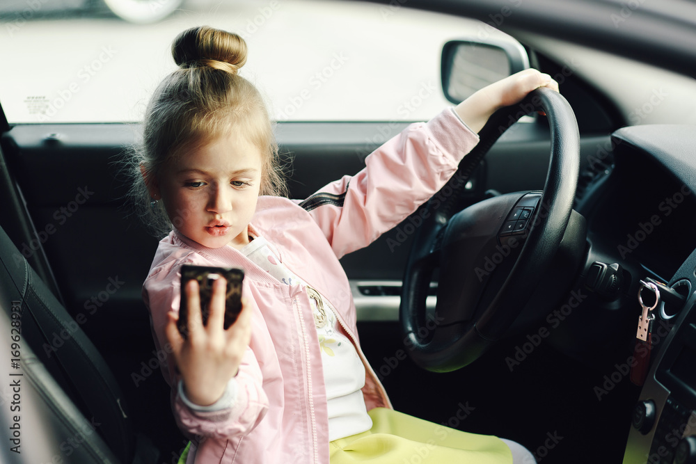 Little cute girl in the car looking at smartphone screen