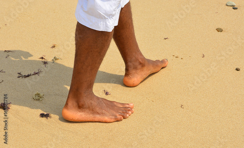 African american man walks on a sand beach. Close up of male feet and golden sand. Beach walk. Summer activity. Beautiful holiday background
