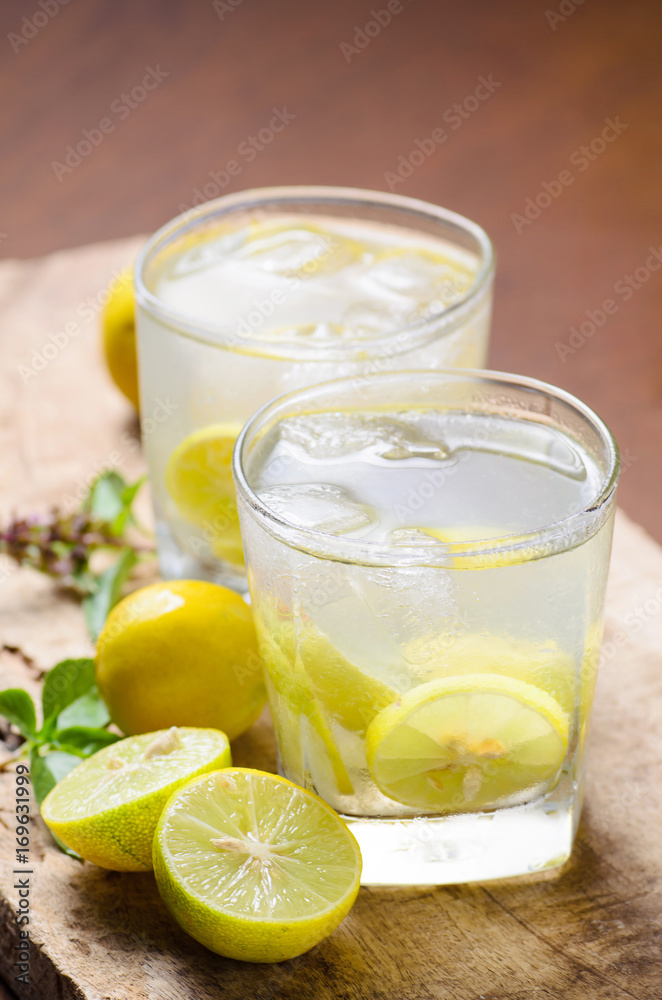 Cold lemonade with ice and fresh slice lemon in the glass on wooden plate,Healthy drink in summer Cold lemonade with ice and fresh slice lemon in the glass on wooden plate,Healthy drink in summer