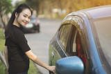 young woman opens door of blue metallic car close up