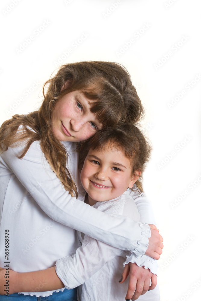 studio portrait of two young happy smiling girls, sisters, over white background studio portrait of two young happy smiling girls, sisters, over white background