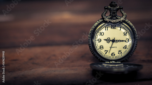 old antique pocket watch showing time on wooden floor with blurred background