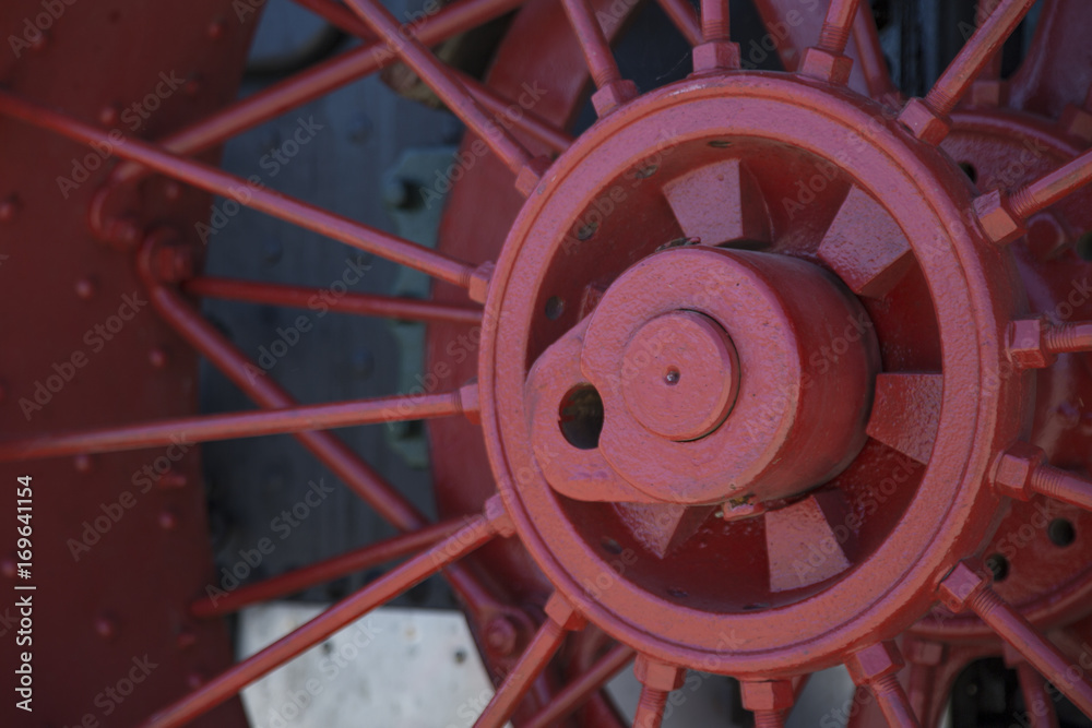 Isolated View of Vibrant Red Painted Antique Spoked Steam Engine Wheel, Against Black Engine Background Backdrop