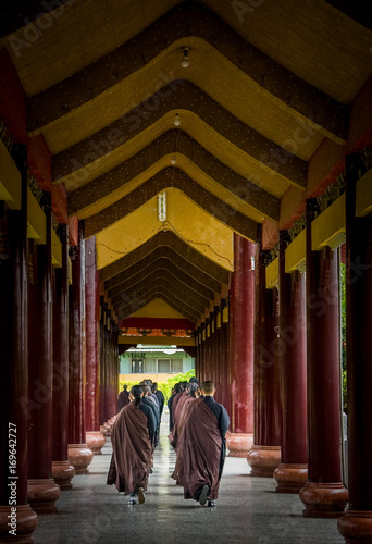 A group of monks walks down an arched pathway
