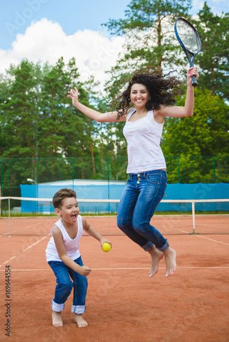 Cute family or mother and son playing tennis and posing in court outdoor © dreamsnavigator