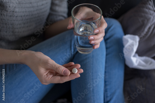 a woman holding a pill and a glass of water
