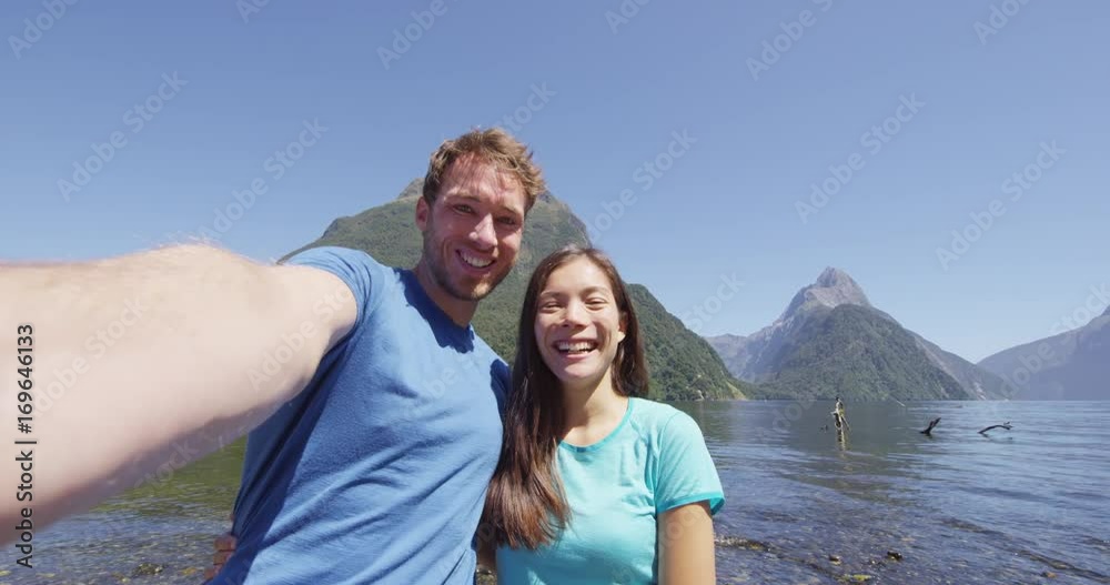 Couple taking selfie video having fun on travel in New Zealand, Milford Sound. Happy woman and man in love travelling taking candid self portrait video, Fiordland, New Zealand. SLOW MOTION. Couple taking selfie video having fun on travel in New Zealand, Milford Sound. Happy woman and man in love travelling taking candid self portrait video, Fiordland, New Zealand. SLOW MOTION.