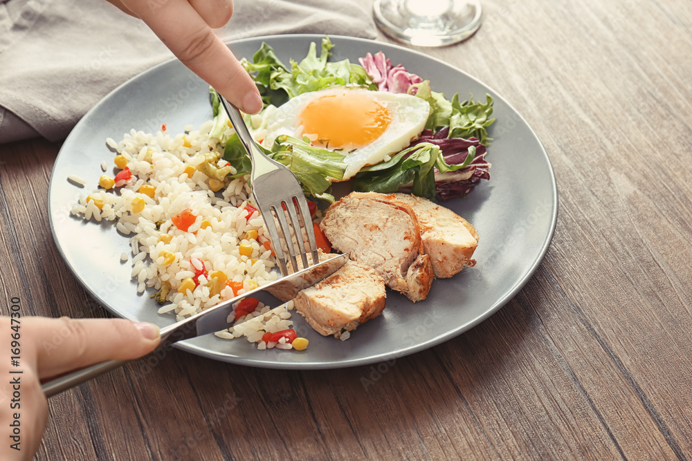 Woman eating delicious rice with meat, egg and mixed salad