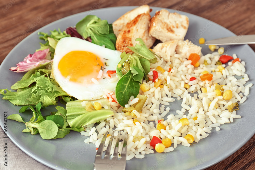 Delicious rice with meat, egg and mixed salad on plate on table Delicious rice with meat, egg and mixed salad on plate on table
