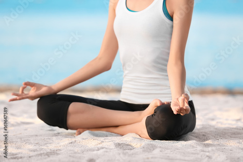 Fototapeta Naklejka Na Ścianę i Meble -  Beautiful young woman practicing yoga at sea resort