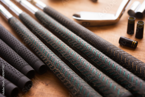 Golf club making or club assembly. Iron club heads and steel shafts with assembly tools on work desk or work bench. Intentionally shot with low key shadows.