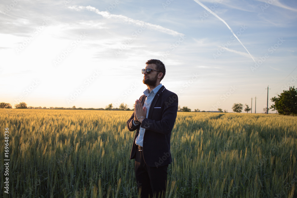 Man in suit relax and meditate in fields during beautiful sunset Man in suit relax and meditate in fields during beautiful sunset