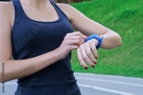 Close up shot of young woman jogger ready to run looking at smartwatch.