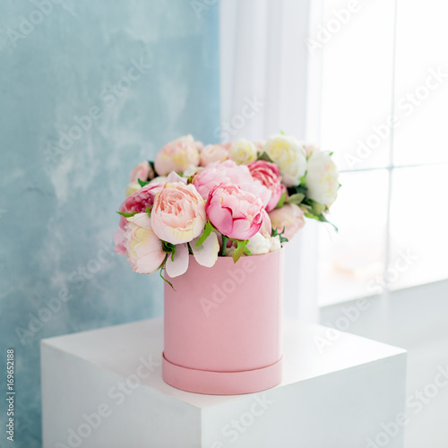 Flowers in round luxury present box. Bouquet of pink and white peonies in paper box. Mock-up of hat box of flowers. Interior decoration in in pastel colors.