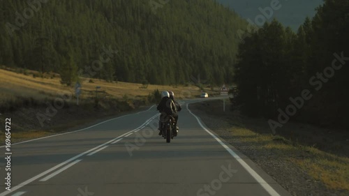 Couple of Motorcyclists on a Motorcycle are Driving along a Beautiful Country Road