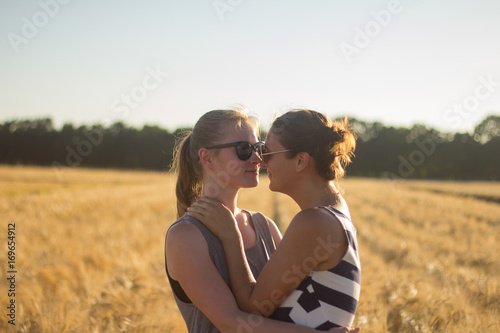 Lovely lesbian couple together, holding hands and having good time in summer wheat fields