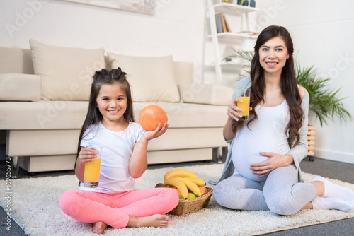 Pregnant woman and daughter with glasses of juice
