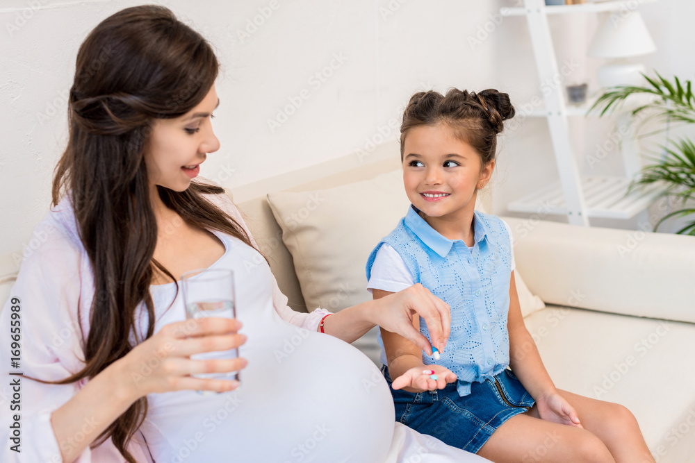 Girl holding out pills to mother Girl holding out pills to mother