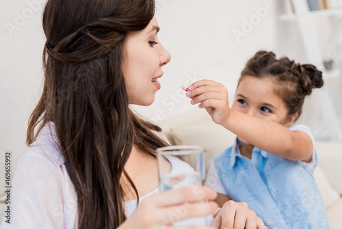Girl feeding pill to mother