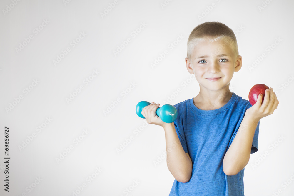 Closeup portrait happy, smiling boy, lifting red apple and dumbbell. The concept of healthy lifestyle. Sports and activities for children. Closeup portrait happy, smiling boy, lifting red apple and dumbbell. The concept of healthy lifestyle. Sports and activities for children.