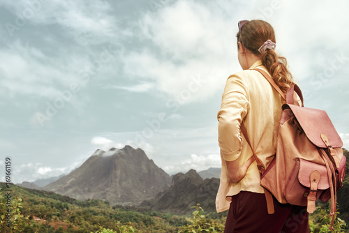 woman tourist in shirt with backpack enjoying mountains view.