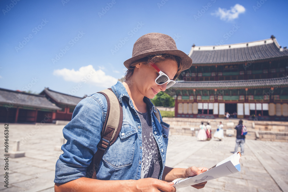 Young woman tourist with map in hand on the background of Asian architecture, travel to Korea, Seoul Asia